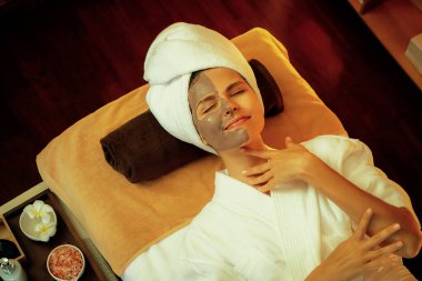 Kaplıca salonunun sakin atmosferi, üst düzey kadın müşteri sıcak mum ışığında kömür kömürü yüz kremi masajıyla kendini yenilemeye çalışıyor. Yüz bakımı ve güzellik konsepti. Sessiz.