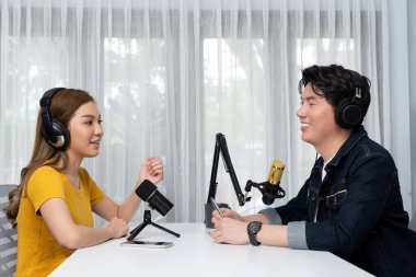 Gülümseyen radyo etkili sunucusu kulaklık takıyor kadın konuşmacı ile röportaj yapıyor sosyal medya internet sitesinden dinleyicilere bilgi paylaşıyor stüdyo kaydında sabah canlı yayın kanalı. İnfobahn.