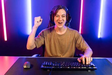 Kazanmak için çevrimiçi oyun oynayan akıllı flama makinesinin sunucu kanalı, neon ışıklı odada seçilen takım yarışması için izleyicilerle birlikte canlı yayında canlı yayında kulaklık takıyor. Bireysel.