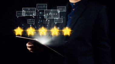 Bir işadamı elinde tabletle karanlık bir ortamda duruyor, beş altın yıldız ve geri bildirim ikonu sergiliyor, yüksek müşteri memnuniyeti ve hizmet mükemmelliğini sembolize ediyor. Dörtgen