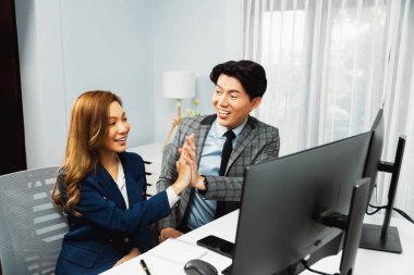 Başarılı gülümseyen Asyalı iş ortakları, hisse senedi borsası veritabanında yan görüntüdeki modern ev ofisinde resmi takım elbise giyerek beşlik çakıyor. İnfobahn.