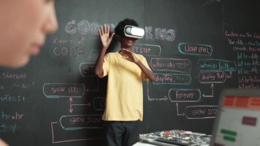 VR kullanan Afrikalı öğrenci meta-dünya ile etkileşime girerken liseli kız el kodlama programını kapat. Zeki çocuk sanal gerçeklik gözlüğü takıyor ve yenilikçi sınıfta video oyunları oynuyor. Öğretim