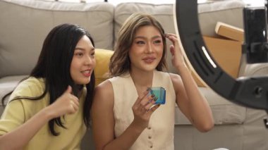 Çekici satıcı çevrimiçi platform kullanarak canlı yayın yaparken ürünü incelemek ve satmak için birlikte çalışıyor. Zeki Asyalı girişimci soruları cevaplarken ürün gösteriyor. Medya. Myrmidon.