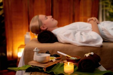 Aromaterapi masajı ambiyansı ya da spa salonu kompozisyon düzeneği bulanık kadınlara odaklı dekor mumları ve spa aksesuarları ile tatil köyü veya otel arka planında keyifli aroma spa masajı yapan. Sessiz.