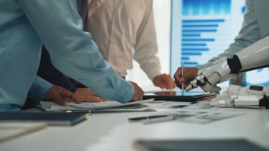 Profesyonellerin teknoloji ve robot kolla birlikte çalıştığı dinamik bir işbirliği sahnesi, ofis ortamındaki modern yenilikleri vurguluyor. Noogenesis