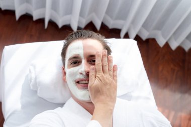 Kaplıca salonunun sakin atmosferi, insan müşterisi modern gün ışığında lüks yüz kremi masajıyla kendini yenileme zevkine kapılıyor. Yüz bakımı ve güzellik konsepti. Sessiz.