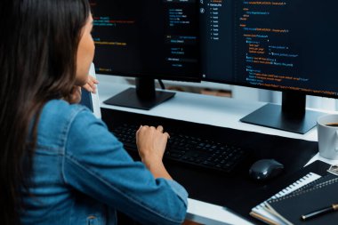 İnternet sitesi uygulamasının kodlama verileriyle birlikte online bilgi yazarak kot gömlek giyen genç Asyalı geliştirici. Güvenlik analizi ile çevrili iki ekran. Taktik.