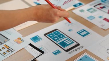 Girişimci şirket çalışanının el odaklı hali ofis çalışma alanındaki akıllı yöneticiye mobil uygulama için kullanıcı arayüzü prototipi sunar. UX UI tasarımcısı kağıt üzerinde simge tasarımının işlevini açıklıyor. Sinerjik