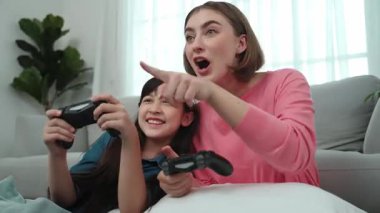 Kafkas anne ve kızı oturma odasında oturup oyun oynuyorlar. Mutlu anne, elinde joystick tutarken akıllı Asyalı kızla vakit geçiriyor. Oyun oynamaktan zevk alıyor. Yaşam tarzı konsepti. Pedagoji.