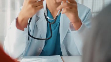 Hasta klinikte ya da hastane ofisinde doktor randevusuna gidiyor. Hastaların nabzını steteskopla kontrol edip risk faktörünü belirleyen doktor semptomları inceliyor. Ağır çekim. Katı.