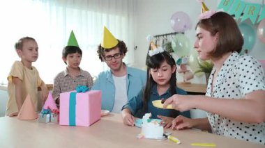 Kafkasyalı anne doğum günü pastasını kesiyor ve babaya verirken tatlıyı ayırıyor. Mutlu aile, kızının doğum gününde masada otururken parti şapkası takar. Özel durum konsepti. Pedagoji.