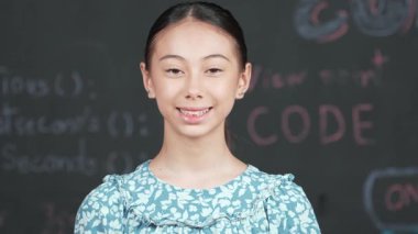 Mühendislik dersiyle tahtaya bakarken kameraya bakan beyaz tatlı bir kız. Kamera sistemi koduna gülümseyen yetenekli öğrenci STEM teknoloji sınıfında arkada yazılı. Öğretim