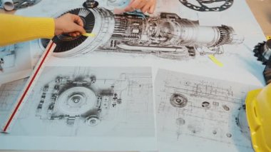 Dinamik mühendislik ekibi, iyi donanımlı bir atölye ortamında hassas aletler ve araçlar kullanarak ayrıntılı teknik çizimler üzerinde işbirliği yapar. SACTR