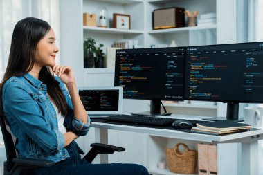 Genç Asyalı bilişim geliştiricisi güzel poz için online bilgi topluyor. Kodlama programı verileriyle birlikte kotlu tişört giyiyor. Güvenlik analizi ile çevrili iki ekran. Taktik.