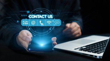 Modern bir iş iletişimi tasviri. Dijital bağlantı seçenekleri olan akıllı bir telefonu tutan bir el, parlak bir dizüstü bilgisayarın arka planına dayanıyor. Dörtgen