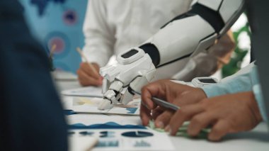 Gelecekçi bir robot kolu, iş raporlarını ve verileri modern bir çalışma alanında analiz etmede, işbirliği ve teknolojik yenilikler sergilemede profesyonellere yardımcı olmaktadır.