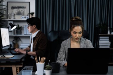 Modern ofiste gece geç saatlerde arka tarafta çalışan iş arkadaşı ile birlikte veri analizi sosyal medya çevrimiçi proje işini rapor etmek için bilgisayara odaklanan iş kadınının ciddi yüzü. İnfobahn.