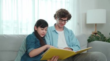 Beyaz bir baba ve tatlı bir kız kanepede otururken masal kitabı okuyorlar. Mutlu bir baba, sevimli bir Amerikan çocuğuna, birlikte zaman geçirirken hayal gücünün gelişmesi için hikaye anlatıyor. Pedagoji.