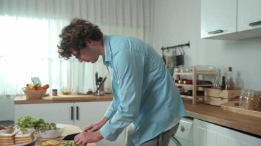 Mutlu baba yemek pişirirken müziğe geçiyor ve modern mutfakta öğle yemeği hazırlıyor. Aktif baba, sebze ve mutfak gereçleri ile çevrili sağlıklı yemek ya da salata yaparken şarkıyla dans ediyor. Pedagoji.