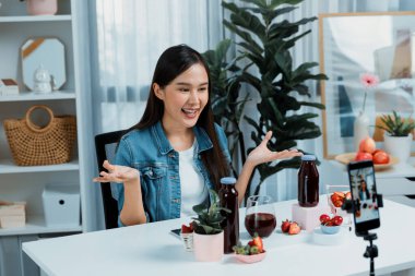 Gülümseyen, güzel Asyalı genç, lezzetli karışık çilek ve kiraz suyu detoksu içeceklerini inceleyen, sosyal medyada özel promosyon satışı için sağlıklı ürünler sergileyen. Taktik.