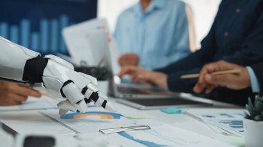 Bir robotik kol modern bir ofiste insan eliyle işbirliği yapar, iş verilerini ve belgelerini analiz eder, teknolojinin çalışma alanına entegrasyonunu gösterir.