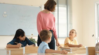 Enerjik zeki öğretmen sınıftaki beyaz çocuğa sınıf çalışmasını anlatırken aynı zamanda çok kültürlü bir öğrencinin derste dinlemesini ve çalışmasını anlatıyor. Aktif öğretmen sınav ya da sınıf çalışmasından bahsediyor. Pedagoji.