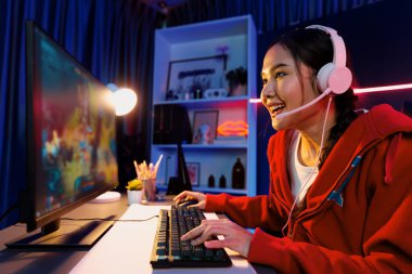 Genç ve güzel Asyalı oyun flamasının sunucu kanalı Moba ile savaş arenasında çoklu oyunlarla oyun oynuyor, neon dijital ışık modern odasında pastel kulaklık takıyor. Taktik.