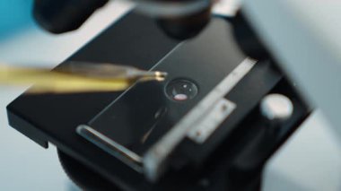 Bilimsel laboratuar araştırmacısı mikroskobik slayt üzerine sıvı örneği bırakır. Tıbbi muayene için ya da yeni teşhis aleti için. Mikrobiyolog ya da tıp çalışanı laboratuarda deney yapıyor. Ağır çekim. Katı.