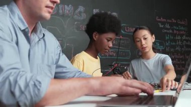 Genç öğrenci BTMM sınıfında öğretmenlik mühendisliği kodları yazarken denetleyiciyi tamir ediyor. Akıllı kız elektronik alet ve karatahta kullanırken eğitmen el bilgisayarı. Öğretim