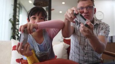 Büyükbaba ve torun birlikte konsol oyunu, eğlence medyası oynuyorlar. Eski kullanım teknolojisi yeni nesil ile iletişim kurar. Nesiller arası uçurum aile bağını güçlendirir. Uyumsuzluk.