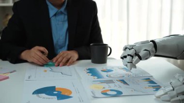 Yapay zeka teknolojisinin veri analizi için insan danışmanlarla işbirliği yaptığı, otomasyon ve uzmanlığın füzyonunu vurguladığı dinamik bir ofis sahnesi. Noogenesis Yapay Zeka