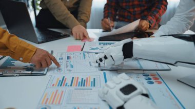 Bir robot kolu, modern bir şirket ortamında karar verme mekanizmasını geliştirmek için bir iş toplantısında takım üyeleriyle işbirliği yapar, grafikleri ve grafikleri analiz eder.