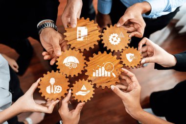 Eller ahşap dişlilerin etrafında toplanır, her biri kilit iş kavramlarını simgeler. İmaj, modern bir şirket ortamında takım çalışması, strateji ve işbirliğini teşvik etmektedir. Dostluk