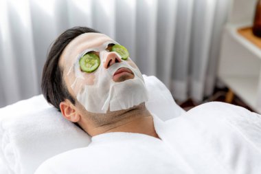 Kaplıca salonunun sakin atmosferi, insan müşterisi lüks salatalıklı yüz maskesi ile kendini yenileme zevkine kapılıyor. Yüz bakımı tedavisi ve güzellik konsepti. Sessiz.