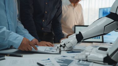 Modern bir ofis sahnesi, insanlara veri analizinde yardım eden, takım çalışmasını vurgulayan ve teknolojinin profesyonel ortamlara entegrasyonunu vurgulayan bir robot kolu gösteriyor. Noogenesis