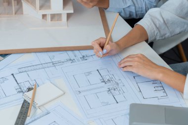 Profesyonel erkek mühendis ev modelini cetvel kullanarak ölçerken güzel bir iş arkadaşı da plan üzerinde yazarak birlikte çalışıyor. Yaratıcı tasarım ve takım çalışması. - Yakın çekim. Tertemiz..