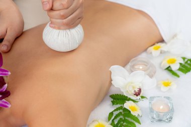 Sıcak bitkisel top spa masaj vücut tedavisi, masör kadın vücuduna nazikçe şifalı bitki torbası bastırıyor. Aromaterapi dinlenme sükuneti ve sükuneti kaplıca salonundaki atmosferi aydınlatıyor. Sessiz.