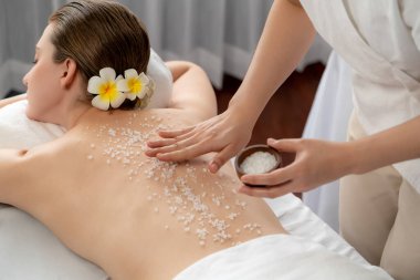 Lüks spa salonlarında sıcak mum ışığında cilt bakımı yaptıran kadın müşteri. Sağlık Spa vücut fırçasında tuz temizleme güzellik tedavisi. Sessiz.