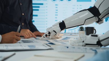 İnsanlar ve robotlar arasındaki işbirliğini gösteren modern bir ofis sahnesi. Bir robotik kol veri analizinde yardımcı olur, iş ortamlarında teknoloji entegrasyonu vurgulanır. Noogenesis