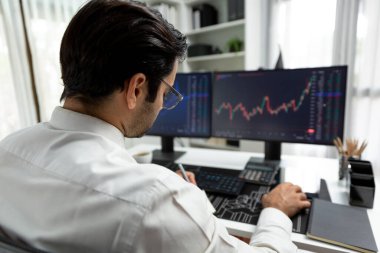 Akıllı tüccar işadamı, modern merkez ofisindeki araştırma pazarında en yüksek kârlı finansal teknolojiye yatırım yaparak bilgisayar üzerinde iki dinamik borsa yatırım ekranını analiz ediyor. Tahmin et..