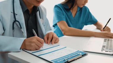 Hastane masasında birlikte çalışan ve tıbbi tedavi planlayan çeşitli profesyonel sağlık görevlileri. Takım çalışması başarılı hastalıklara ve hastalıklara yol açar. Ağır çekim. Katı.