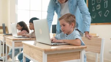 Çeşitli öğrenciler yapay zeka yazılımı kullanırken, Kafkas öğretmeni enerjik çocuğa kodlama konusunda yardım ediyor. Çocuklar oturma ve programlama sistemi. Sevimli bir öğrenci şifreyi öğreniyor. Pedagoji.