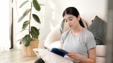 Kanepede oturan bir kadın ders kitabı okuyarak sosyal ve mesleki teknoloji bilgisini artırır ya da akıllı bir anne olmak için çocuk yetiştirir. Hayat boyu öğrenme konsepti. Uyumsuzluk.