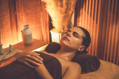 Beyaz kadın müşteri stres önleyici spa masajının keyfini çıkarıyor ve lüks otel ya da otelde sıcak mum ışığında güzellik teniyle eğleniyor. Sessiz.