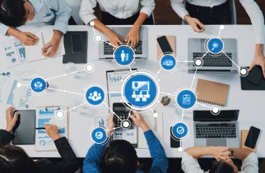 Modern ofis ortamında veri analizi ve etkili iletişimi vurgulayan canlı bir iş yönetimi toplantısı, dizüstü bilgisayarlar ve dijital grafikler etrafında takım işbirliğini gösteriyor. Dostluk