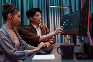 Bilgi teknolojisi geliştiricileri modern ofisteki neon ışık odasında verileri çevrimiçi olarak çalıştıran akıllı web sitesi geliştirme kodlayıcı sistemine işaret ediyorlar. İnfobahn.