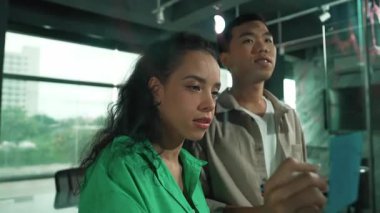 Hispanik çalışanlar, yatırımcılar ayakta durup dinlerken pazarlama fikirleri üretmeye başlarlar. Kadın lider beyin fırtınası iş planı sunuyor. Cam duvardaki yapışkan nota yazılmış bir strateji. Yönlendirici