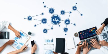 Perde ve kağıtlarda veri analizlerinin gösterildiği ve yeniliklerin teşvik edildiği bir iş stratejisi oturumuna katılan profesyonelleri gösteren dinamik bir toplantı sahnesi. Dostluk