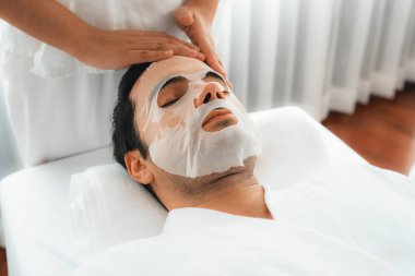 Kaplıca salonunun sakin, modern gündüz atmosferi. Kadın müşteri yüz maskesi takarak kendini yenilemeye çalışıyor. Yüz bakımı ve güzellik kozmetolojisi prosedürü. Sessiz.