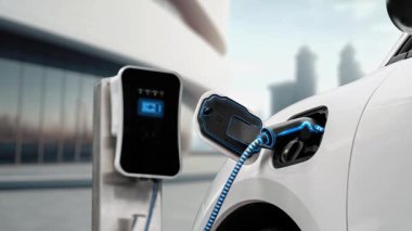 Modern ve fütüristik bina arka planında akıllı EV şarj istasyonundan elektrikli araba şarj oluyor. Alternatif ve sürdürülebilir enerji kullanan şarj edilebilir EV arabaların teknolojik gelişimi. İnceleyin